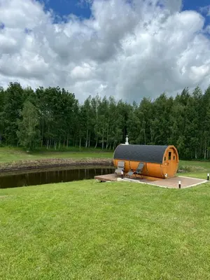 a small building with a roof on a grass field at Atostogų namelis Stebuliuose in Stebuliai