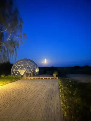 a large glass greenhouse at night with a blue sky at Atostogų namelis Stebuliuose in Stebuliai