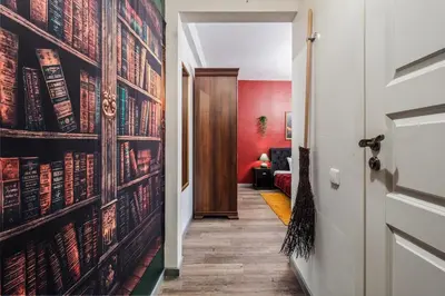 a hallway with a red wall with books on it at Blue Oasis and Wizard's Hideaway apartments in Kaunas
