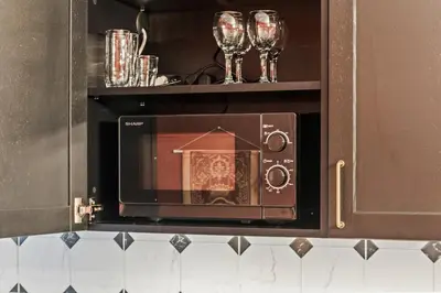 a microwave in a kitchen with two wine glasses at Blue Oasis and Wizard's Hideaway apartments in Kaunas