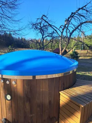 a hot tub with a blue top on a wooden deck at Šilas in Degučiai