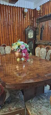 a wooden table with flowers on it with a clock at Šilas in Degučiai