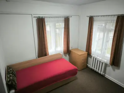 a bedroom with a red bed and two windows at Kambarių nuoma 