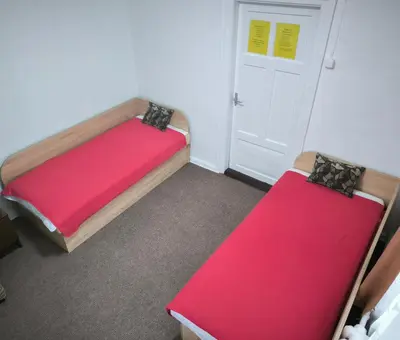 a room with two beds with red sheets and a door at Kambarių nuoma 
