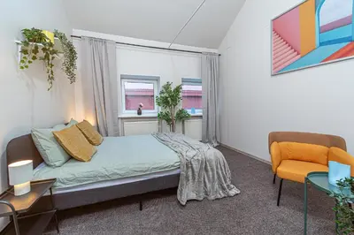 a bedroom with a bed and a chair and a window at Urban Style Old Town in Kaunas