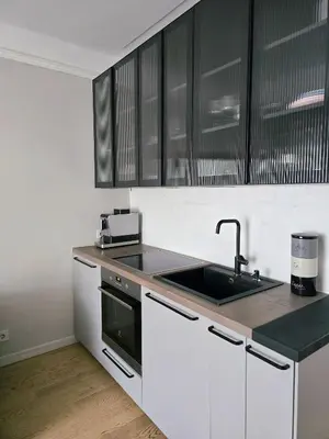 a kitchen with white cabinets and a sink at Downtown Apartment Rentals in Šiauliai