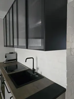 a kitchen with a sink and black cabinets at Downtown Apartment Rentals in Šiauliai