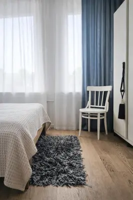 a bedroom with a bed and a chair and a rug at Downtown Apartment Rentals in Šiauliai