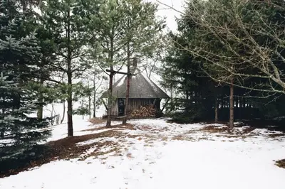 a cabin in the woods with snow on the ground at Pakaso sodyba in Kirdeikiai