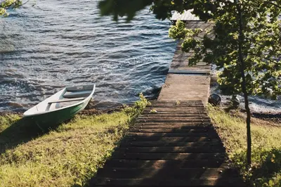 a boat sitting on the side of a dock next to the water at Pakaso sodyba in Kirdeikiai