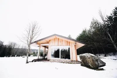 a small cabin in the snow with a large rock at Pakaso sodyba in Kirdeikiai