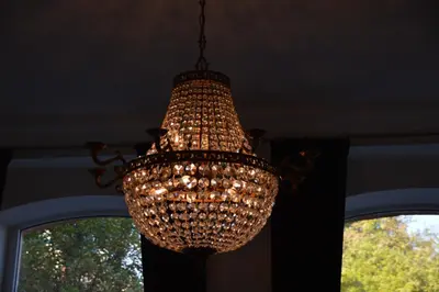 a chandelier hanging from a ceiling with two windows at Cosy Old Vilnius in Vilnius