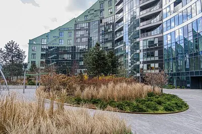 a large building with a garden in front of it at Cute apartment Konstitucijos ave in Vilnius