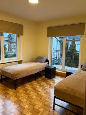 two beds in a room with two windows at Park Hostel in Šiauliai