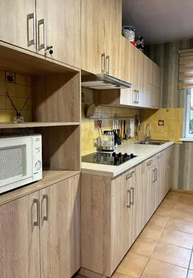 a kitchen with wooden cabinets and a microwave at Park Hostel in Šiauliai