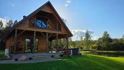 a log cabin with a large window on a grass field at Ramaus poilsio sodyba in Petruniškis