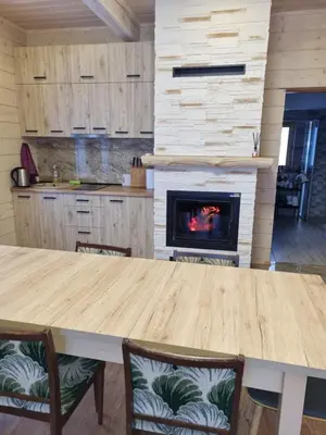 a kitchen with a table and a fireplace at Ramaus poilsio sodyba in Petruniškis