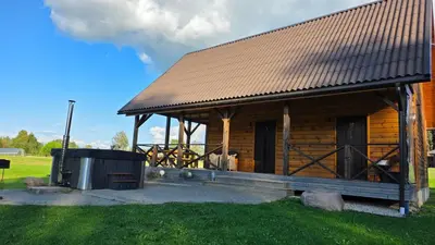 a log cabin with a large porch and a trash can at Ramaus poilsio sodyba in Petruniškis