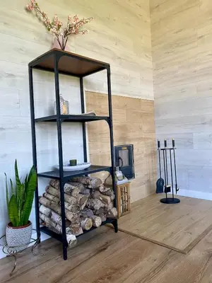 a black shelf with a pile of fire wood at Sauna for celebration and leisure in Grygaytse