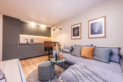 a living room with a blue couch and a kitchen at Cozy flat in Antakalnis in Vilnius