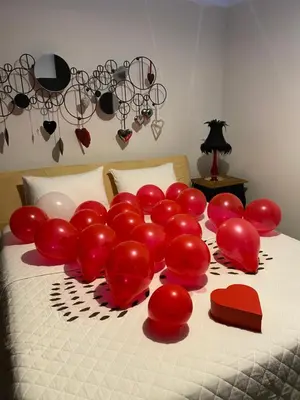 a bed with a bunch of red balloons on it at Gulbės Apartamentai in Anykščiai