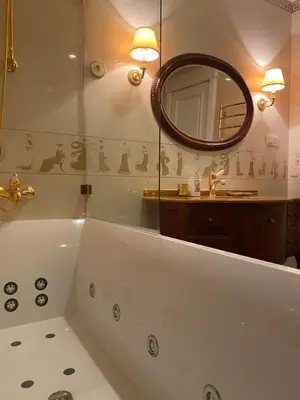 a bathroom with a tub and a sink and a mirror at Gulbės Apartamentai in Anykščiai
