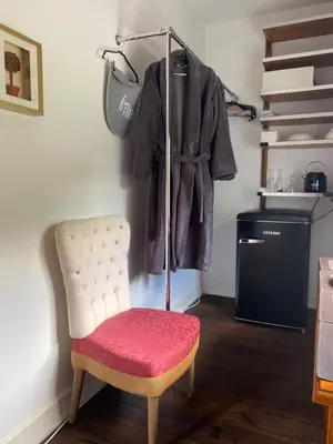 a room with a chair and a coat on a rack at Gulbės Apartamentai in Anykščiai
