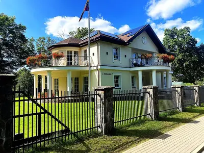 a white house with a fence in front of it at Gulbės Apartamentai in Anykščiai