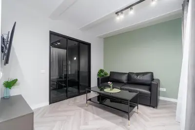 a living room with a black leather couch and a table at Old Town Jacuzzi in Vilnius