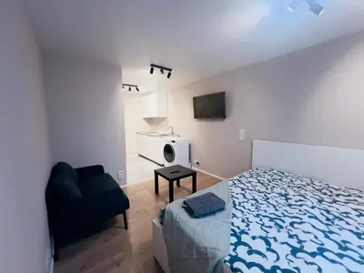 a bedroom with a bed and a tv and a chair at studio apartment in Vilnius
