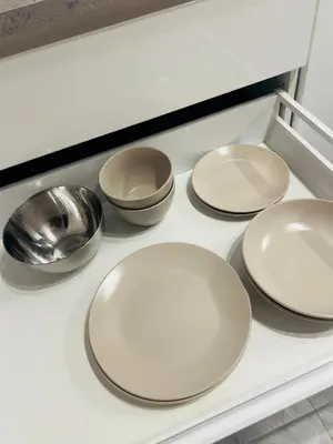 four white plates and bowls on a kitchen counter at studio apartment in Vilnius