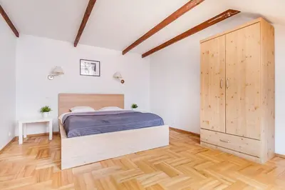 a bedroom with a bed and a wooden cabinet at Old town apartment with 3 bedrooms by URBAN RENT in Vilnius