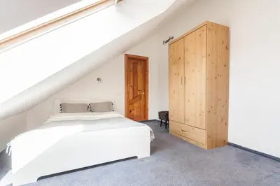 a bedroom with a white bed and a wooden cabinet at Old town apartment with 3 bedrooms by URBAN RENT in Vilnius