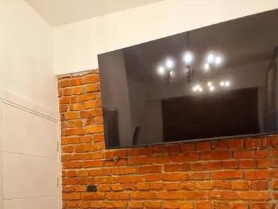 a large flat screen tv on a brick wall at Kaunas Studios - RentA 19 in Kaunas