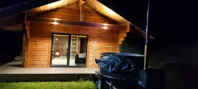 a small wooden cabin with a front door at night at Tauro Pirtis in Vainiūnai