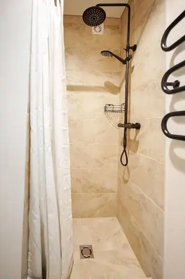 a shower with a shower curtain in a bathroom at Stylish white salad studio near the city center in Vilnius