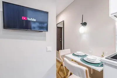a kitchen and a dining room with a tv on a wall at Stylish white salad studio near the city center in Vilnius