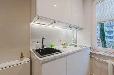 a white kitchen with a sink and a window at Stylish white salad studio near the city center in Vilnius