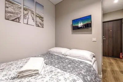 a bedroom with a bed and three pictures on the wall at Stylish white salad studio near the city center in Vilnius