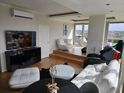 a living room with white furniture and a flat screen tv at Skyline Pearl Vilnius in Vilnius