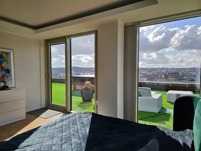a bedroom with a bed and a large glass window at Skyline Pearl Vilnius in Vilnius