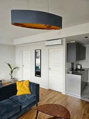 a living room with a blue couch and a kitchen at Skyline Pearl Vilnius in Vilnius