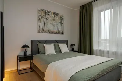 a bedroom with a large bed and a window at Lake Town Apartment in Vilnius