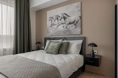 a bedroom with a bed with a painting on the wall at Lake Town Apartment in Vilnius