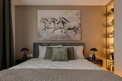 a bedroom with a bed with a painting of four horses at Lake Town Apartment in Vilnius