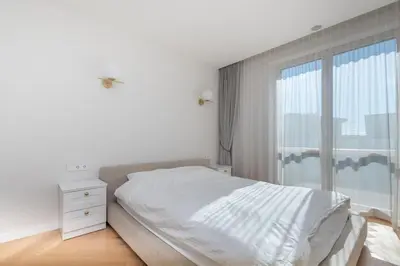 a white bedroom with a bed and a window at The Zen Den Apartment in Uzupis in Vilnius