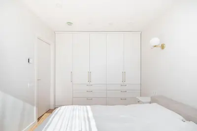 a white bedroom with white cabinets and a bed at The Zen Den Apartment in Uzupis in Vilnius