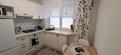a kitchen with white cabinets and a table and a window at Šiauliai Central Vytauto Apartment in Šiauliai