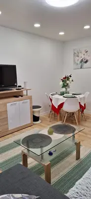 a living room with a table and a tv at Šiauliai Central Vytauto Apartment in Šiauliai