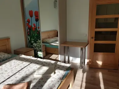 a bedroom with two beds and a mirror with red tulips at Rodante Apartments in Druskininkai